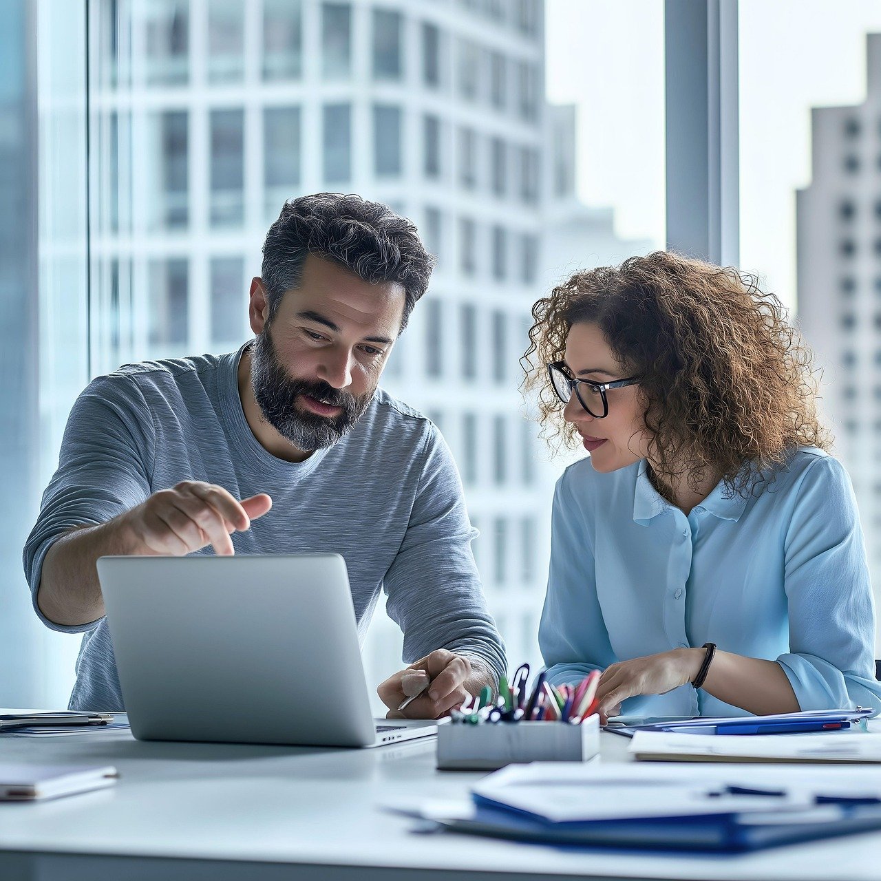Professionals discussing work on laptop in office